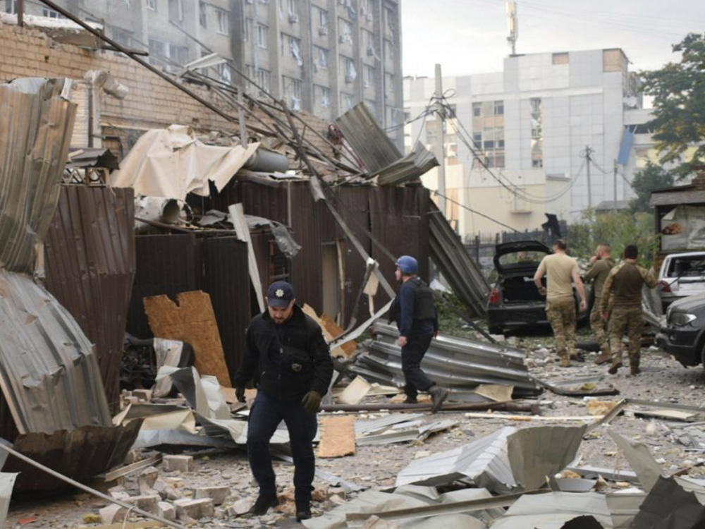 In this photo provided by the National Police of Ukraine, a police officer and a rescue worker walk in front of a restaurant RIA Pizza destroyed by a Russian attack in Kramatorsk, Ukraine, Tuesday, June 27, 2023.