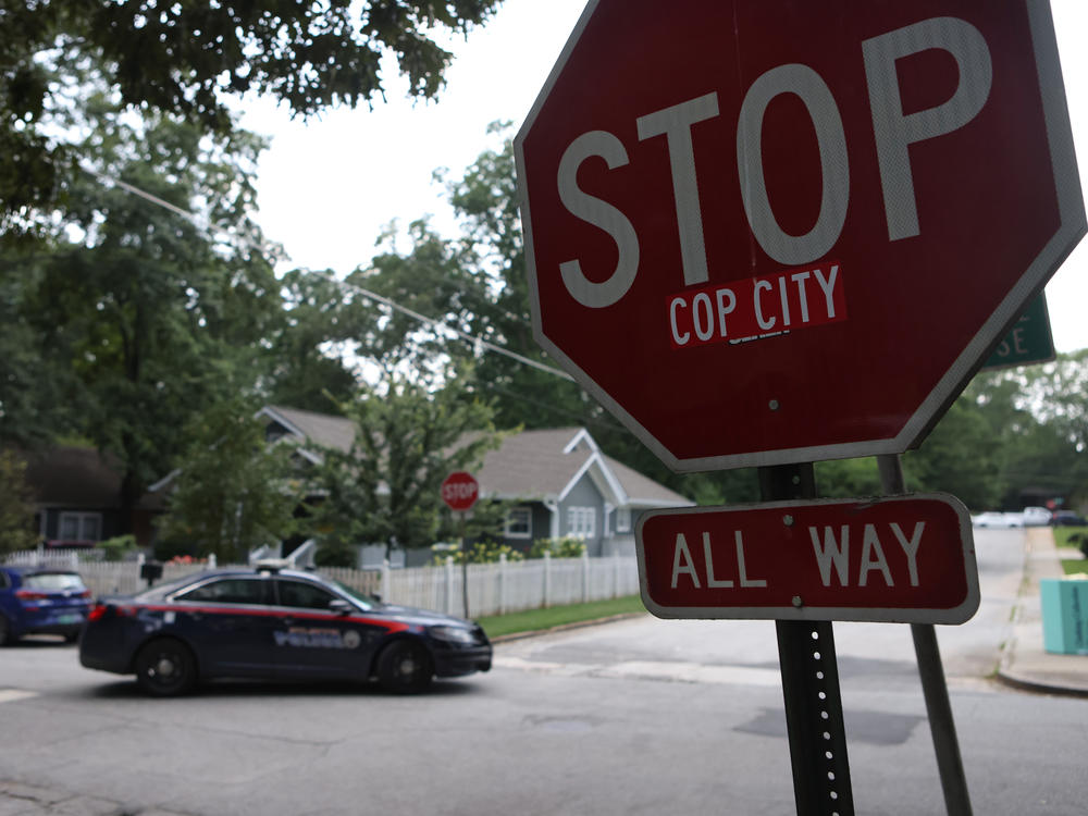 A police car drives through an intersection near Brownwood Park on Saturday where a stop sign has been modified in opposition to the Atlanta Public Safety Training Center that protesters refer to as 