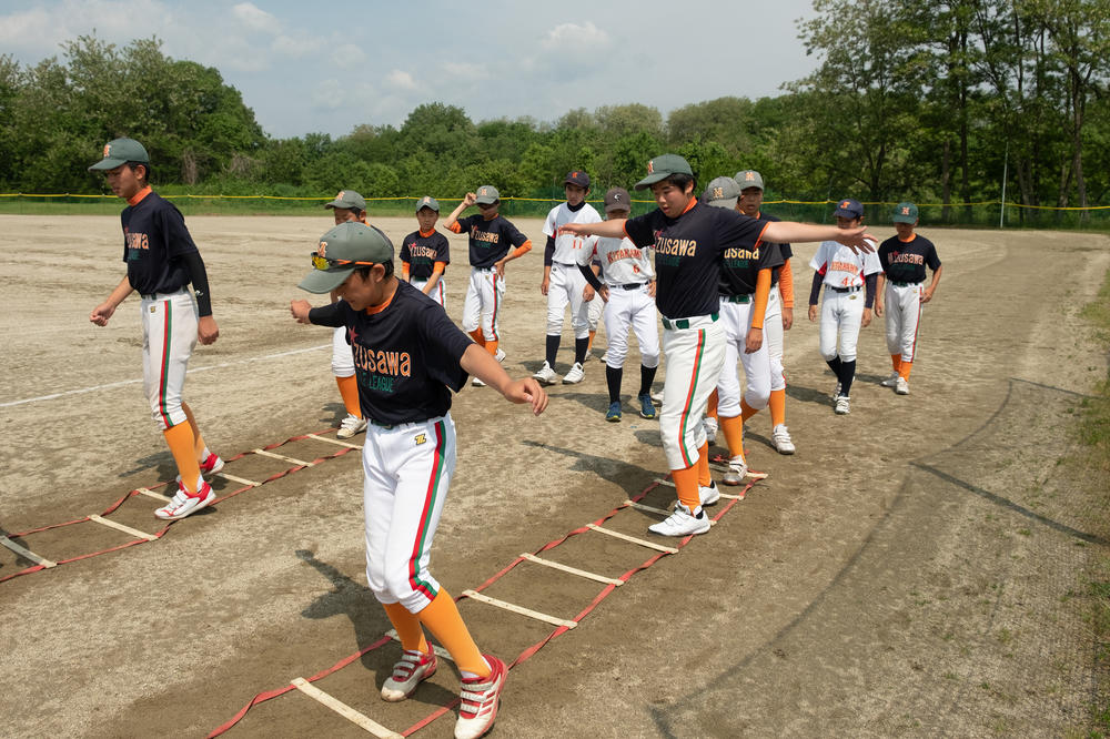 Players with the Mizusawa Pirates hop over a ladder for agility drills during a weekend practice. Young baseball players in Japan use repetitive drills to hone skills such as bunting or executing double plays.