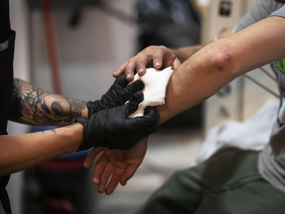 A nurse treats a man's skin wounds in a community outreach storefront in the Kensington neighborhood of Philadelphia in May. Xylazine, a powerful animal sedative that's moving through the illicit drug supply in the U.S., is causing gruesome skin wounds and scrambling longstanding methods for treating addiction and reversing overdoses.