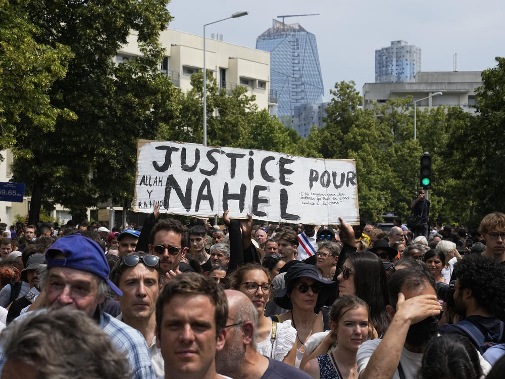 Demonstrators carry a poster reading 