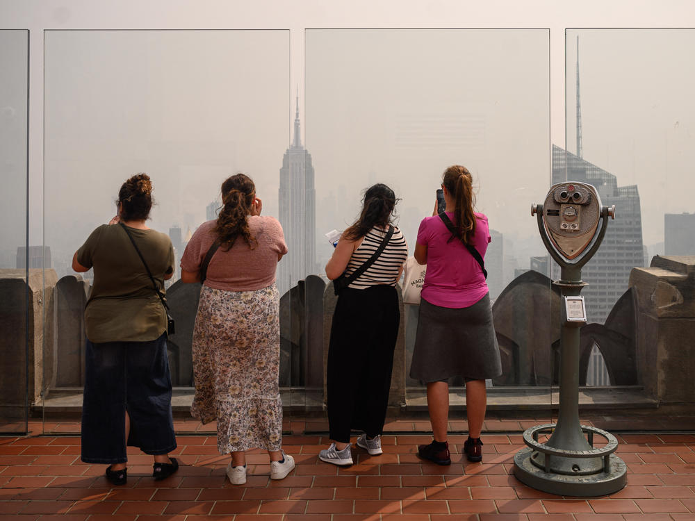 People at a viewing deck of the Rockefeller Center gaze at the Manhattan skyline on Friday during heavy smog brought by wildfire smoke from Canada.