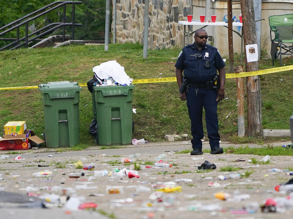 A police officer stands in the area of a mass shooting in the Southern District of Baltimore on Sunday.