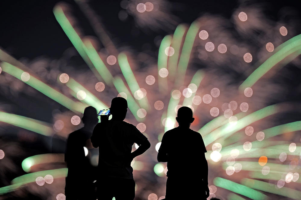 People watch distant fireworks from a park on July 4, 2022, in Kansas City, Missouri.