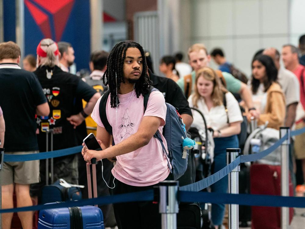 Travelers wait in line at Hartsfield-Jackson Atlanta International Airport in Atlanta on June 30, 2023, ahead of the 4th of July holiday weekend.  Consumers are traveling and eating out more though they are paring down spending in other ways.