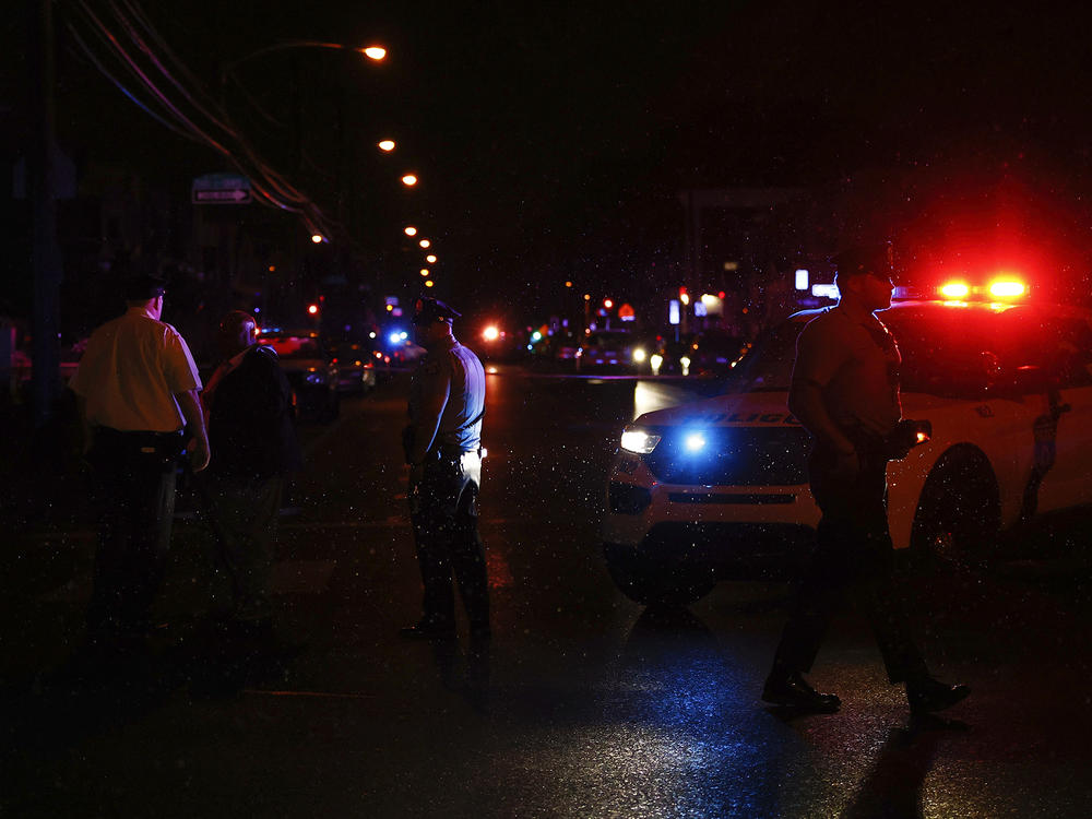 Philadelphia police stand at the intersection of 56th Street and Kingsessing Avenue after multiple people were shot in Southwest Philadelphia, late Monday, July 3, 2023.