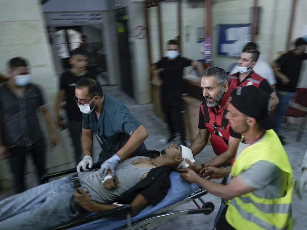 Palestinians carry a wounded man shot by Israeli fire shortly after he threw a bomb toward an Israeli army vehicle during a military raid in the Jenin refugee camp, a militant stronghold in the occupied West Bank, Tuesday.
