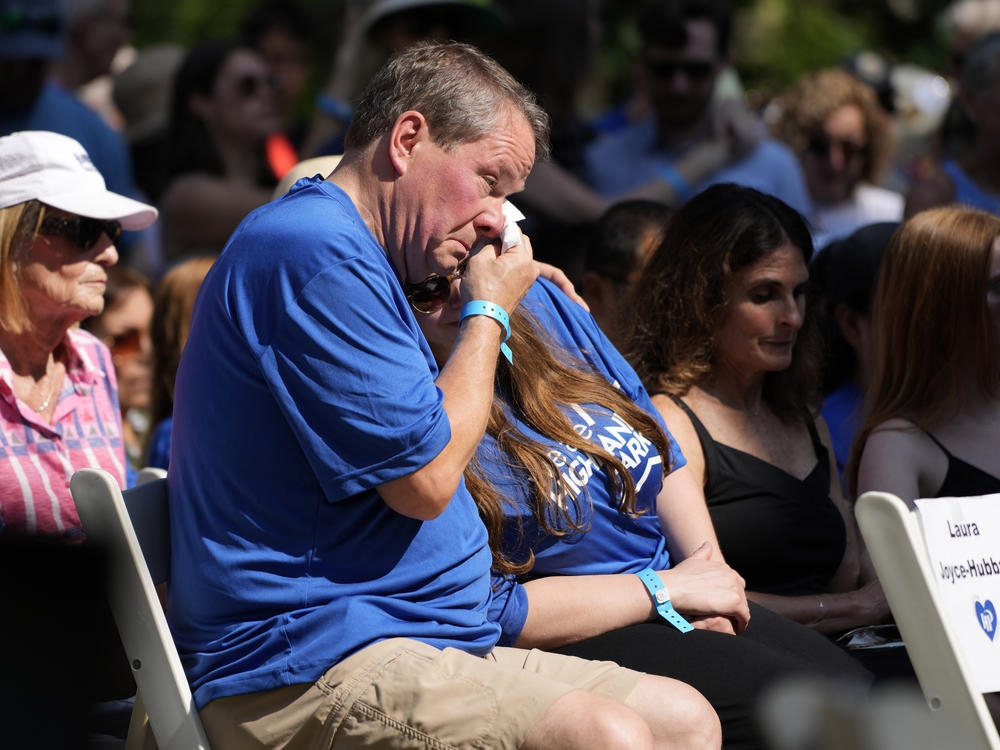 A visitor wipes tears at a remembrance ceremony in Highland Park, Ill., Tuesday, one year after a shooter took seven lives at the city's Fourth of July parade.