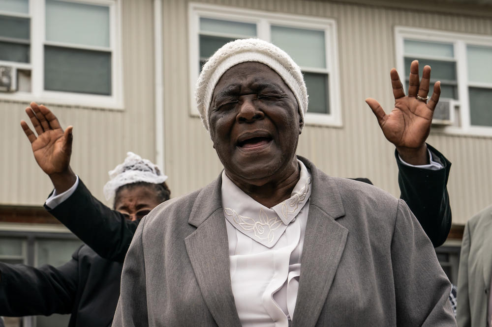 Mother Myrtle Watts with the Kingdom Life Church prays at the site of a mass shooting in the Brooklyn Homes neighborhood on Sunday in Baltimore, Maryland. Two people were killed and 28 others were wounded during the shooting at a block party on Saturday night.
