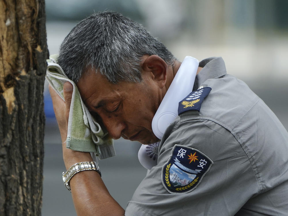 A security guard wipes sweat from his brow in Beijing, on July 3, 2023. Record-breaking heat is unfolding around the world because of human-caused climate change and the cyclic climate pattern El Niño.