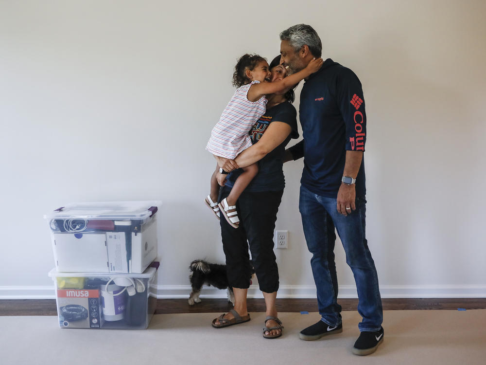 During the pandemic, the number of young children in urban U.S. counties saw significant declines. Joyce Lilly, center, holds her granddaughter Paige alongside her husband, Anil, at their new home in July 2020 in Washingtonville, N.Y.