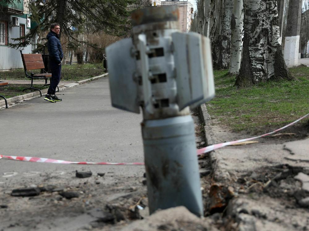 A man walks past an unexploded tail section of a 300mm rocket which appear to contained cluster bombs launched from a BM-30 Smerch multiple rocket launcher embedded in the ground after shelling in Lysychansk, Lugansk region on April 11, 2022.