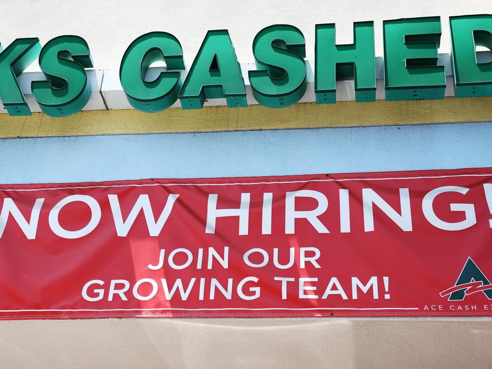 A 'Now Hiring' sign is displayed outside a check cashing shop in Los Angeles on June 2, 2023. Employers added 209,000 jobs last month, slowing down from previous months but still marking respectable growth.