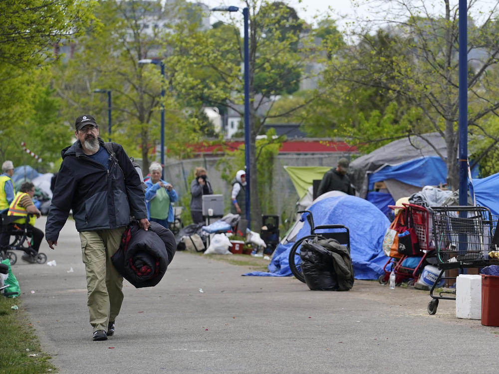 A man carries a sleeping bag at a homeless encampment in Portland, Maine, in May, before city workers arrived to clean the area. State officials say a lack of affordable housing is behind a sharp rise in chronic homelessness.