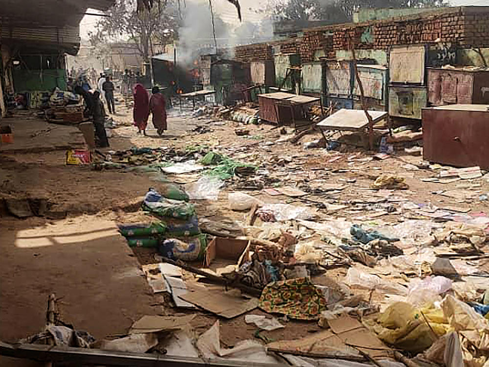 People walk among scattered objects in the market of El Geneina, the capital of West Darfur, as fighting continues in Sudan between the forces of two rival generals, on April 29.