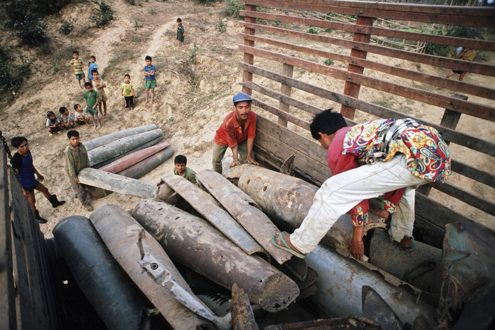 Lao scrap dealers buy metal cluster bomb casings and plane parts from local villagers in Laos, in 1991.
