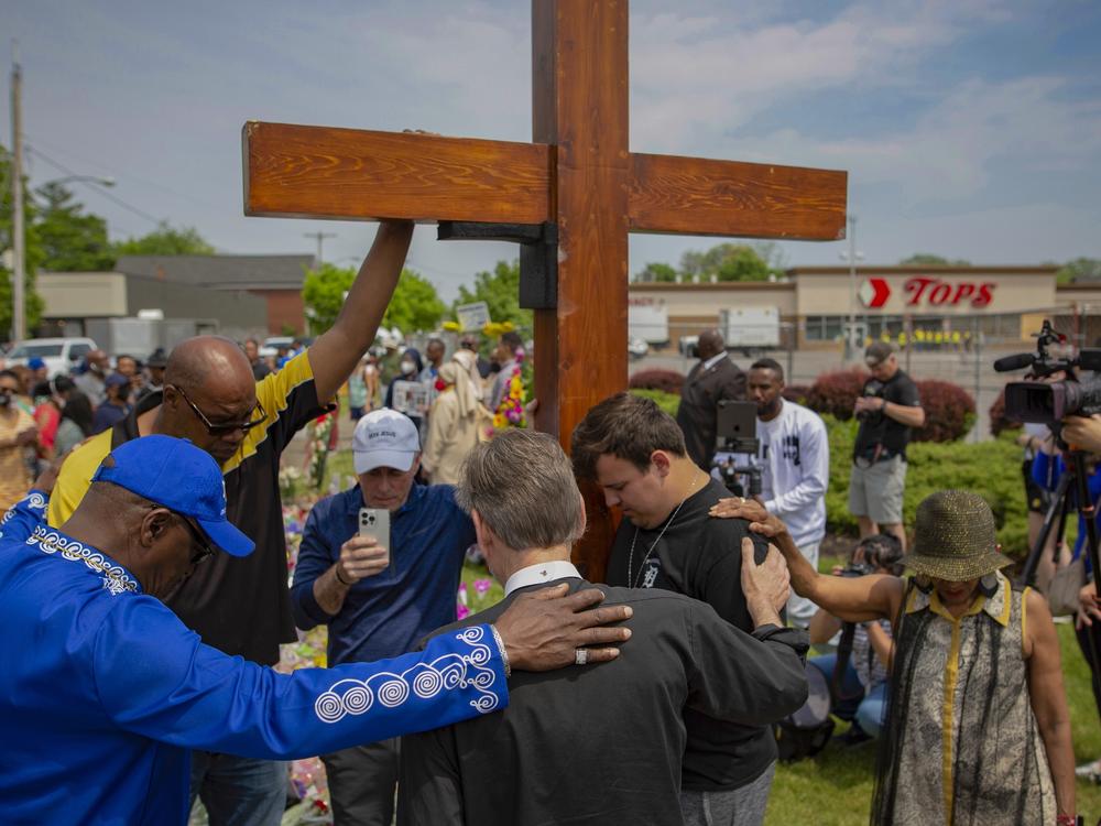 A new civil lawsuit filed Wednesday by families of the Buffalo Tops mass shooting victims targets a number of social media companies, gun retailers, a body armor manufacturer and the mass shooter's parents. Here, a group prays at the site of a memorial for the victims of the Buffalo supermarket shooting outside the Tops Friendly Market on Saturday, May 21, 2022, in Buffalo, N.Y.