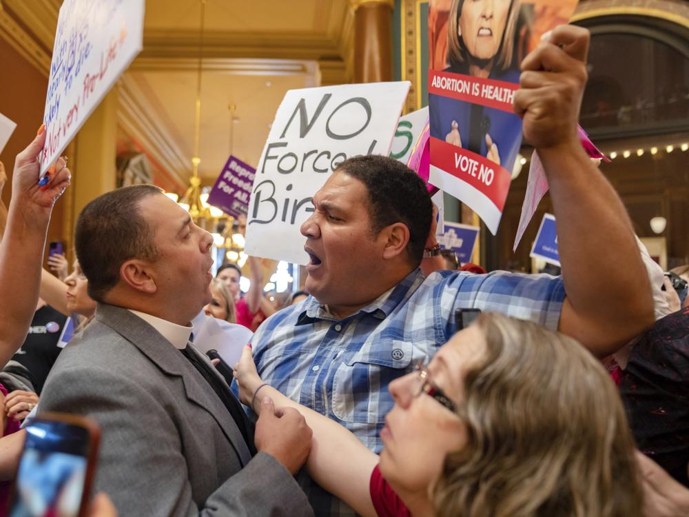 Pastor Michael Shover of Christ the Redeemer Church in Pella, Iowa, left, argues with Ryan Maher, of Des Moines, as protesters clashed in the Iowa State Capitol rotunda, while the Iowa Legislature convened for a special session on July 11, 2023.