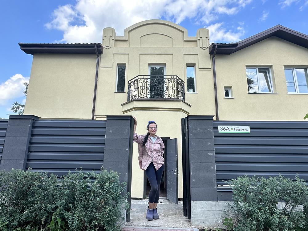 Olha Kornych, 58, stands in front of her newly rebuilt home on Vokzalna Street in Bucha, a suburb of Kyiv. Her home was among the many that were badly damaged or destroyed in Russia's full-scale invasion in February 2022.