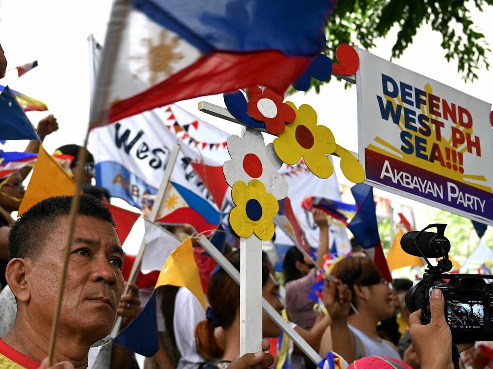 Protesters wave flags and hold placards in front of the Chinese Consulate in Makati, Metro Manila on July 12, 2023, during a demonstration held to mark the seventh anniversary of an international arbitral ruling that voided China's historical claims to the South China Sea, including the nine-dash line.