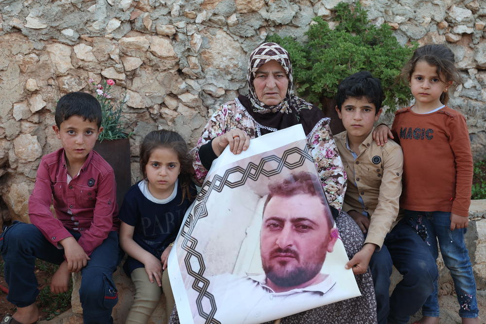 Rutaiba Qurmo poses with a portrait of her late son, Khaled Mustafa Qurmo, and his children in the Syrian village of Turlaha on June 24. He and his cousin were killed by U.S. airstrikes during the 2019 raid on Baghdadi's compound.