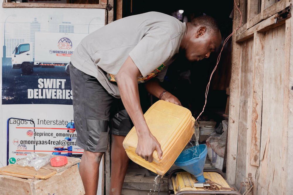 Beautician Kehinde Adebajo pours fuel into the generator in front of his salon. When the government ended its massive fuel subsidy in May, fuel prices quickly shot up.