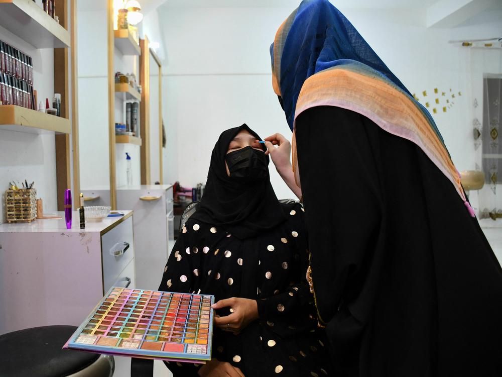 An Afghan beautician applies makeup to a client at a beauty salon in Mazar-i-Sharif.