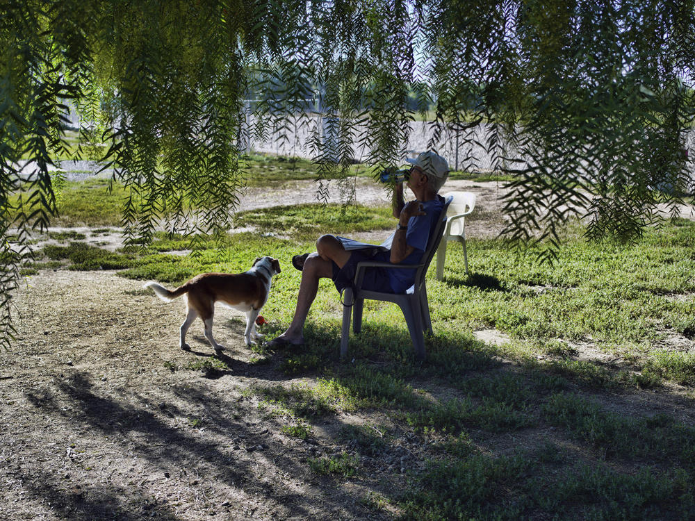 A man sits with his dog in the shade in an attempt to beat the heat in Los Angeles on Thursday.