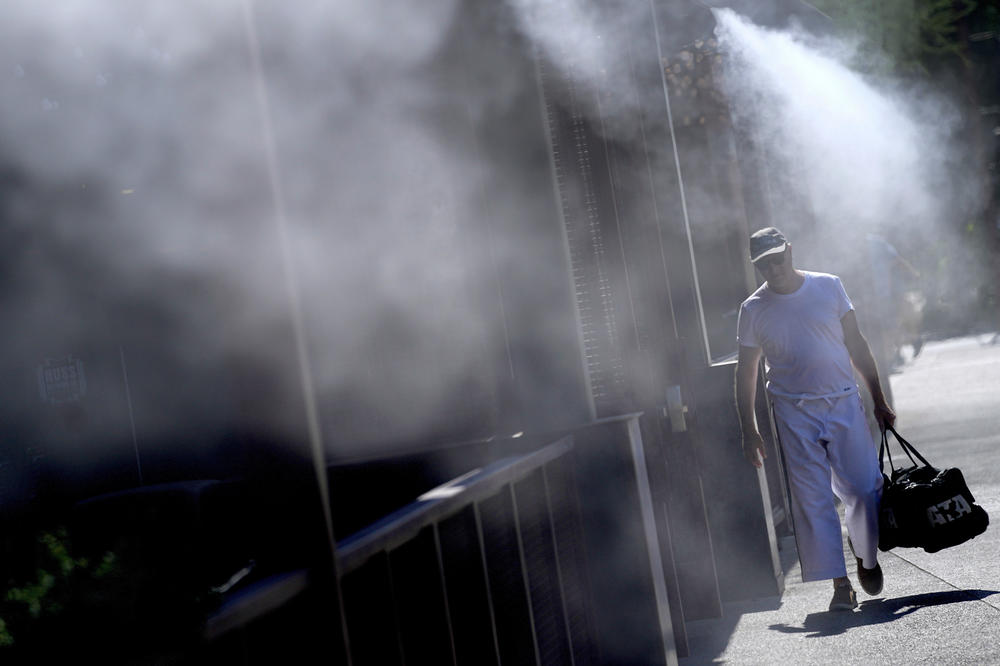 A man walks along a sidewalk under the misters on Friday in downtown Phoenix.
