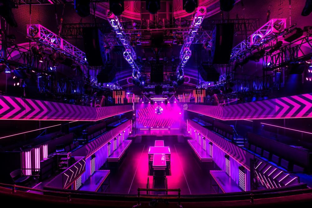 Three hundred audience members stand on a dance floor, while others sit directly above it or in the balcony.