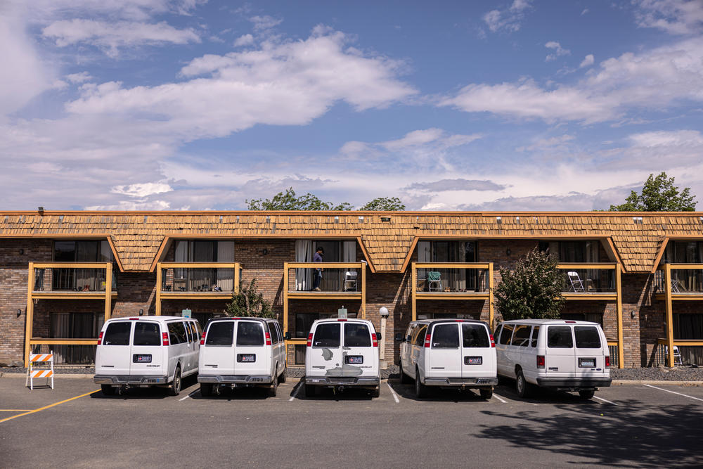 Transport vans are parked in a row at the FairBridge Inn in Yakima, Wash. Employers must pay for transportation for guest workers to from their work sites.