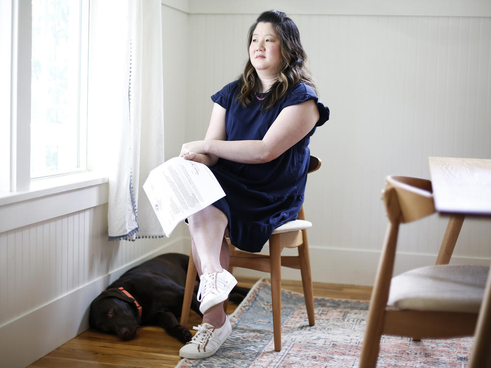 Bridget Narsh holds one of the letters demanding payment from the North Carolina attorney's general office. Her son's service dog, Koko, specially trained to help people with autism, is at her feet.