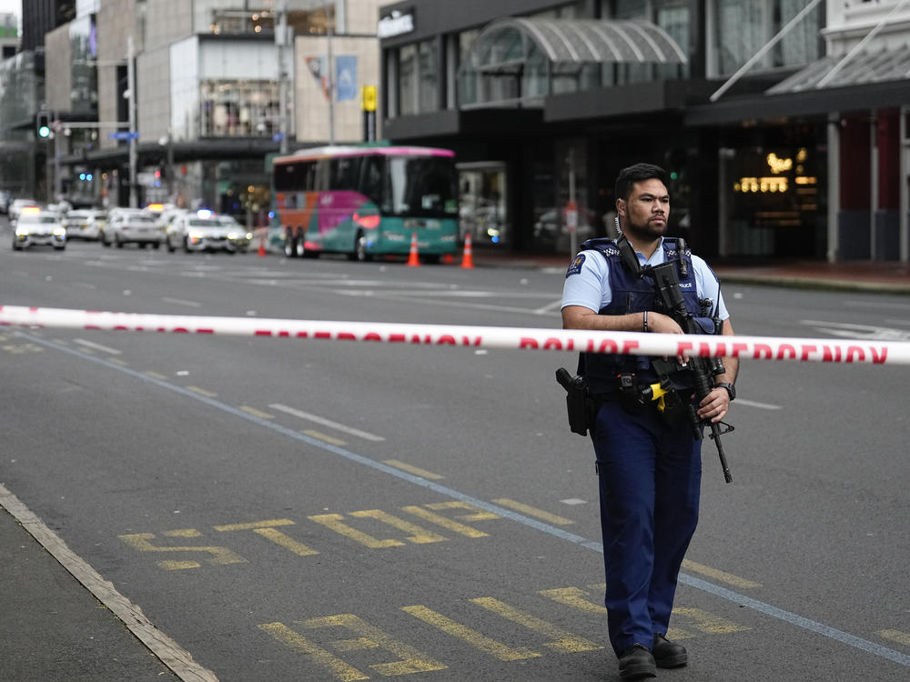 An armed New Zealand police officer stands at a road block in the central business district following a shooting in Auckland, New Zealand, Thursday, July 20, 2023. New Zealand police are responding to reports that a gunman has fired shots in a building in downtown Auckland.