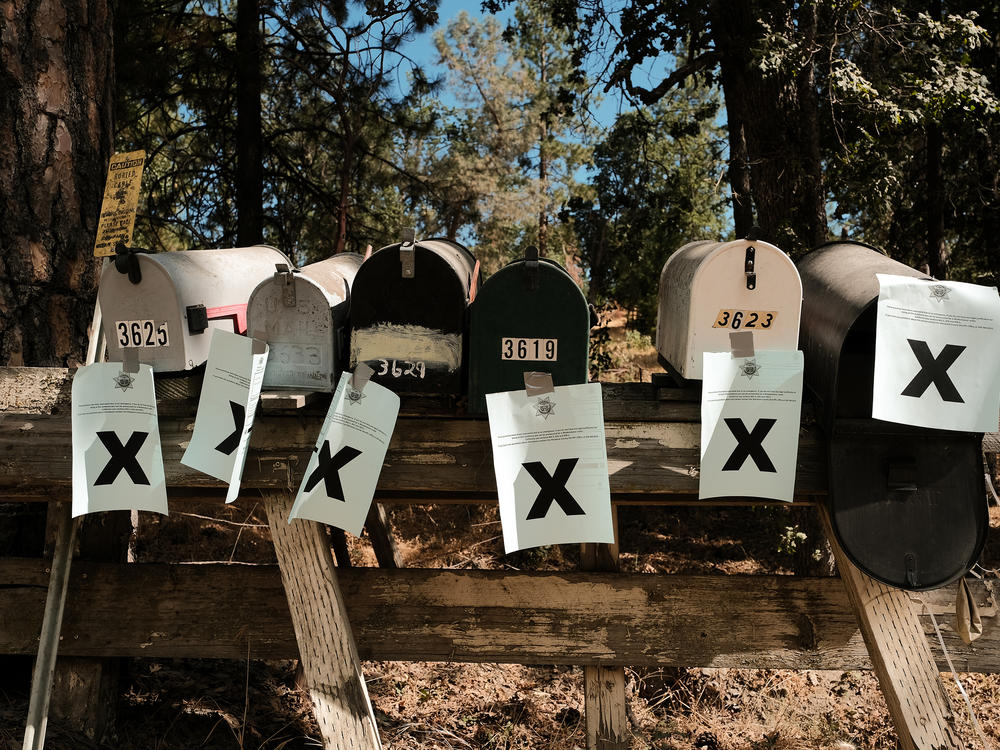 A row of mailboxes tagged with evacuation notices during the Oak Fire in Mariposa, Calif., in July 2022. Many residents in the area are losing their home insurance because of rising wildfire risk.