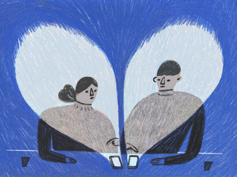 Two people sit next to each other swiping on their phones.