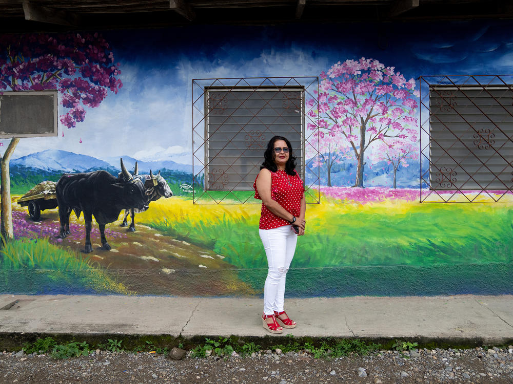 Jacqueline Trejo, mayor of Macuelizo, walks past one of the town's murals. The pink flowering tree that's depicted is the source of the town's name. She wanted to improve the quality of life there but lacked the funds to fulfill her plans.