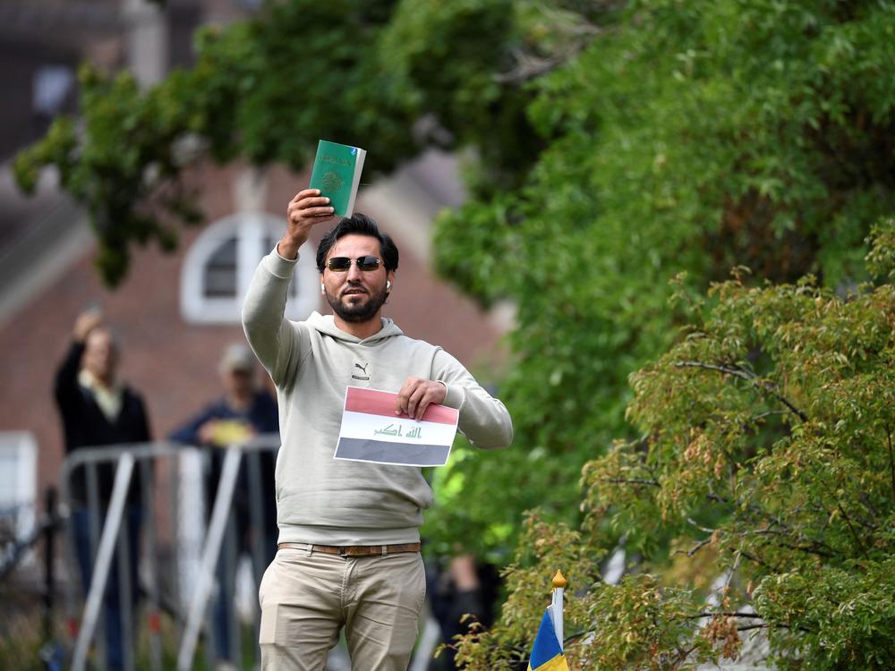 Salwan Momika holds up the Quran and a sheet of paper showing the Iraqi flag outside the Iraqi Embassy in Stockholm, Sweden, Thursday. Iraq warned Sweden it would cut diplomatic relations if a Quran-burning protest is allowed to go ahead in Stockholm, after protesters stormed and torched the Swedish Embassy in Baghdad overnight.