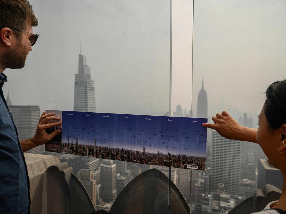 Heavy smoke from Canada's wildfires has put a thick haze over large parts of the U.S. this summer. Here, visitors to New York City hold a map showing city landmarks on a clear day as they stand on the viewing deck of Rockefeller Center in late June.
