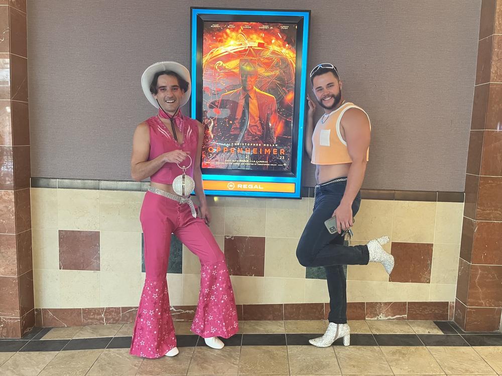 Jeffrey Williams (left), who rented out a <em>Barbie</em> screening for his birthday, and Andrew Roof pose next to an <em>Oppenheimer</em> poster at the Regal Gallery Place in Washington, D.C., on Friday night.