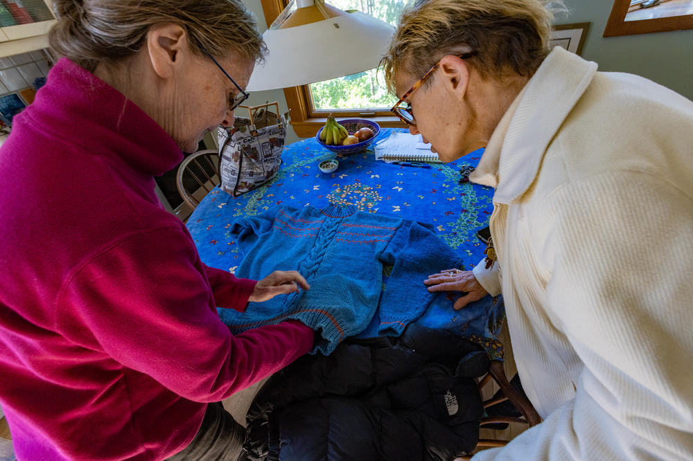 Diane Pullen (right) looks at the sweater her late mother started, and volunteer Dawn Drevers (left) completed.