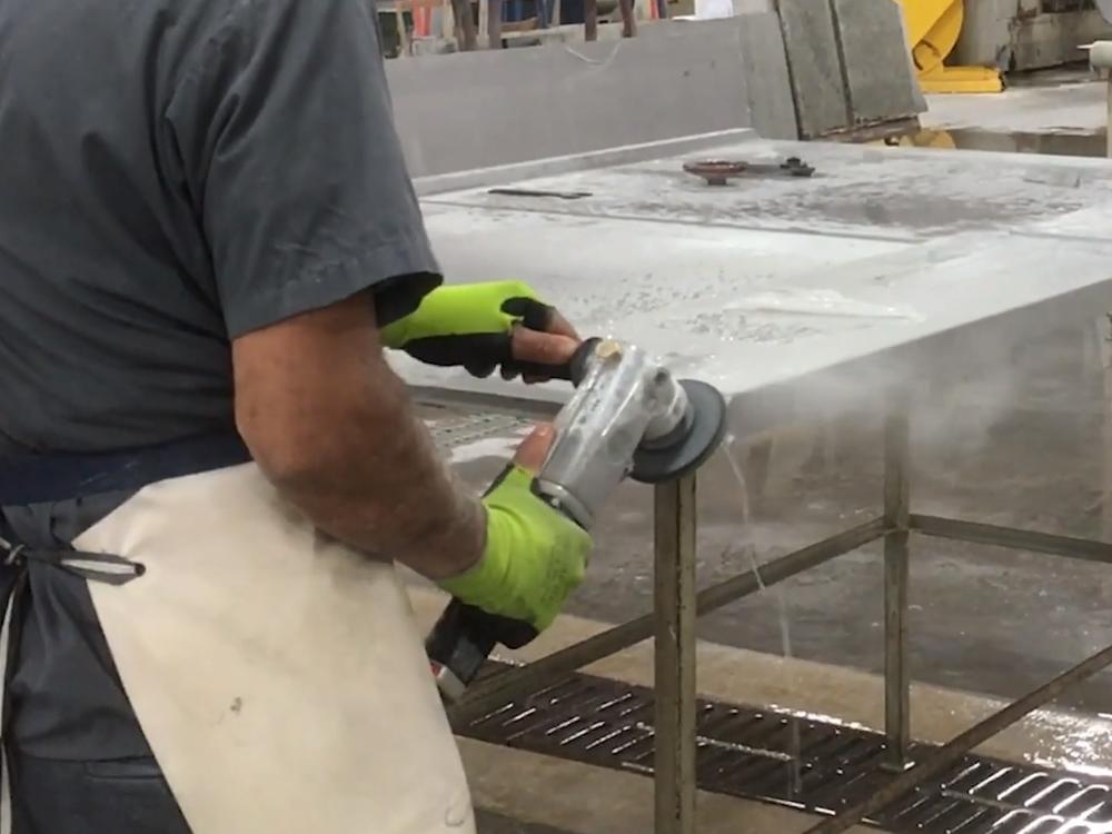 This image, from a video produced by government safety researchers, shows a countertop worker using a machine with a spray of water that's intended to control dust.