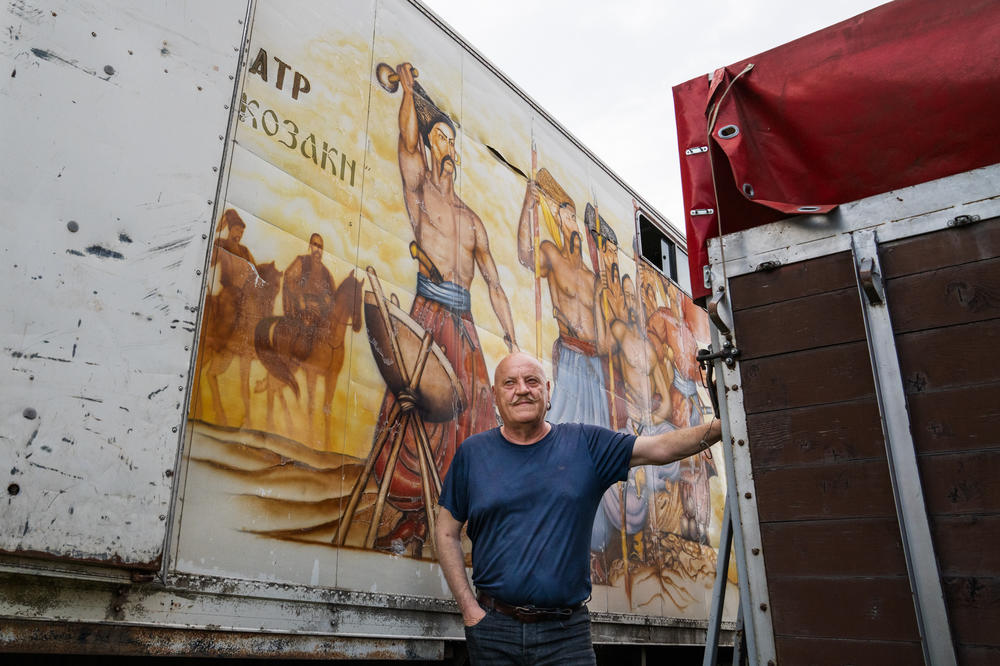 Kopishinskyi stands in front of a mural depicting Cossacks with long mustaches painted on the side of a trailer that they once used to transport horses to shows.