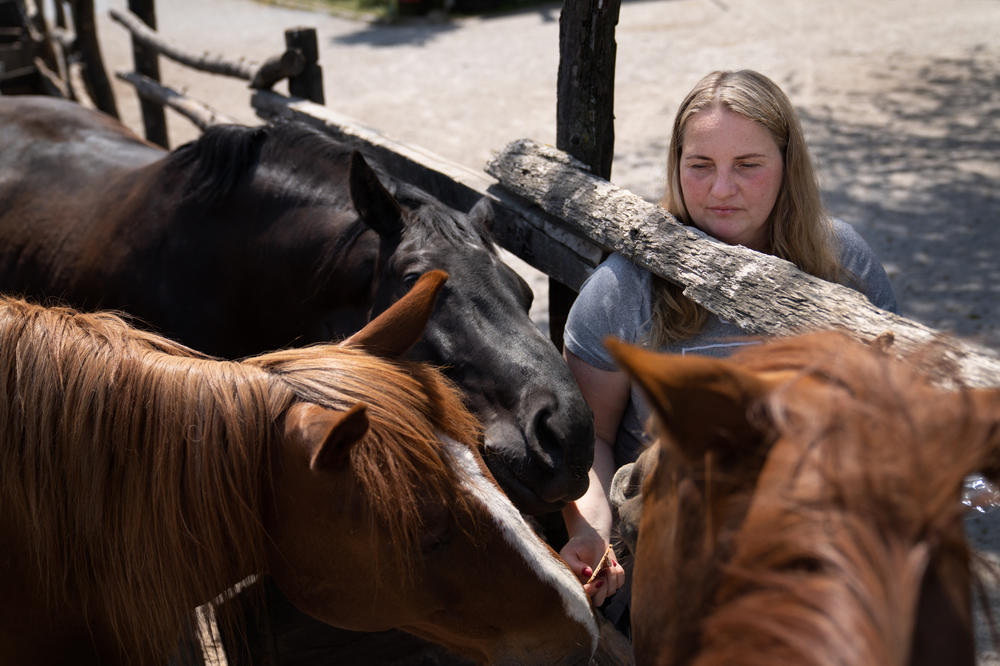 Anastatasiya Kopishynska, feeds the horses on the farm.