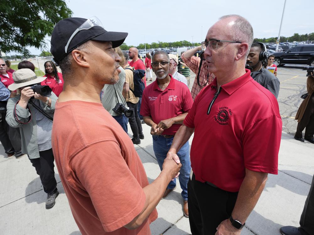 Autoworker Kevin Winston, left, talks with United Auto Workers president Shawn Fain outside the General Motors Factory Zero plant in Hamtramck, Mich., on July 12.