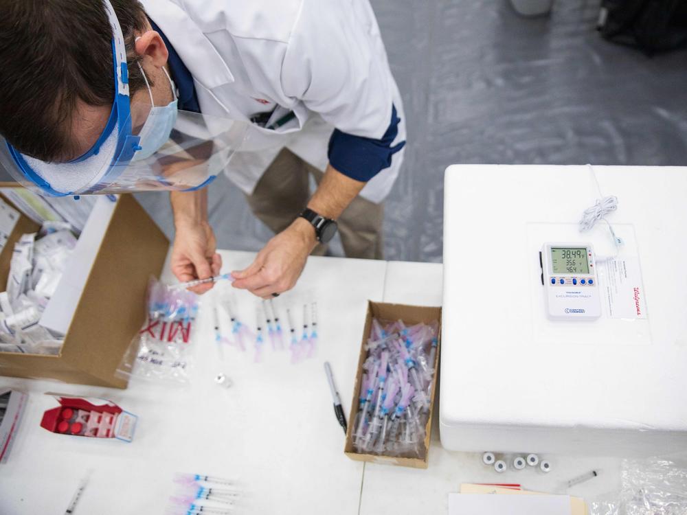 A new study finds a gap in excess deaths opened between Republicans and Democrats in 2021, after vaccine access was widened to all adults. Here, a Walgreens worker prepares vaccine shots for school staff in Dayton, Ohio, in February 2021.