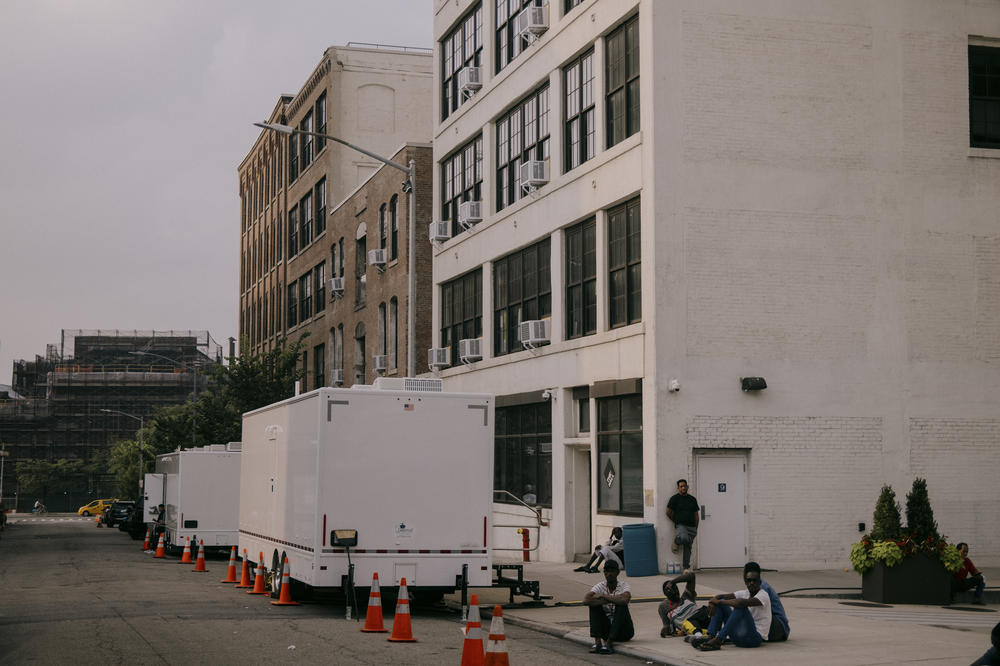 Asylum seekers spill out onto Hall Street outside of the Clinton Hill Shelter. Two shower units stand outside at 47 Hall Street. Brooklyn, New York, U.S., on Wednesday, July 19, 2023.