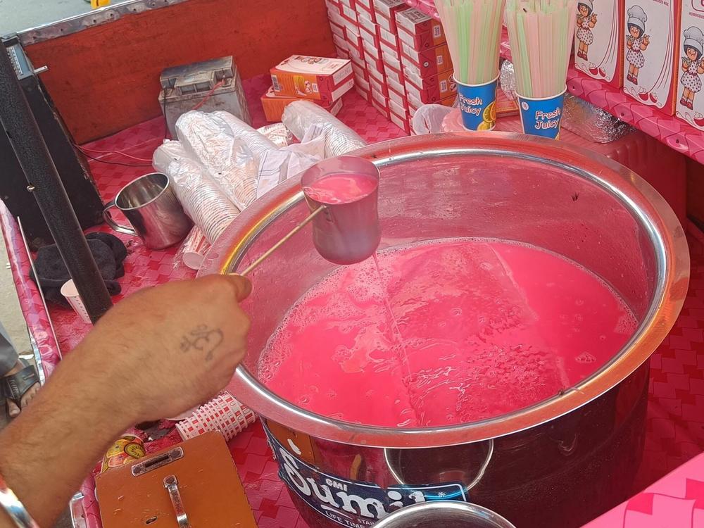 A vendor in Old Delhi mixes a pink beverage of Rooh Afza diluted with milk.