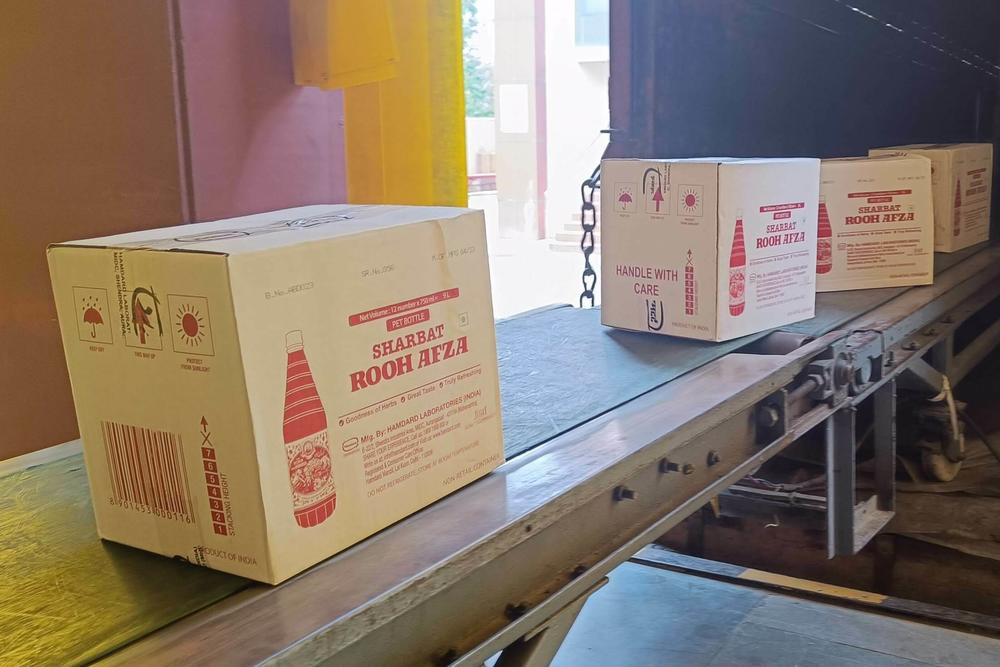 Cartons of Rooh Afza bottles move up a conveyor belt and into a truck, ready to be dispatched from Hamdard's factory near Delhi.