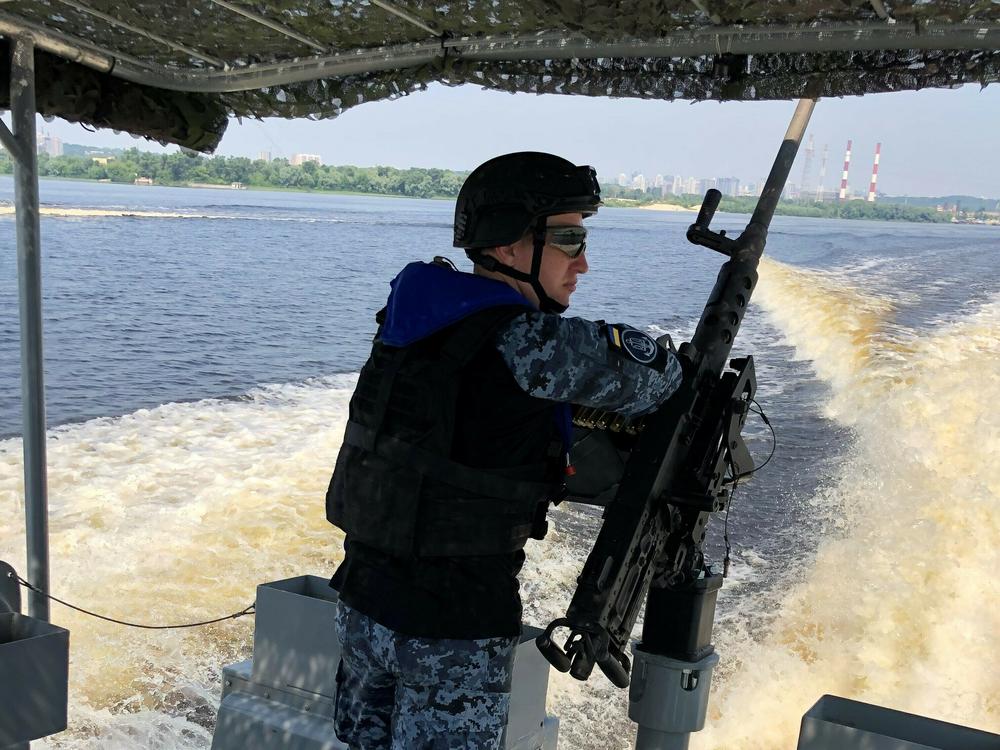 A Ukrainian sailor stands watch at a machine gun on the back of a patrol boat in the Dnipro River off Kyiv. Russia seized or destroyed much of Ukraine's navy, but the country is trying to rebuild its sea forces.