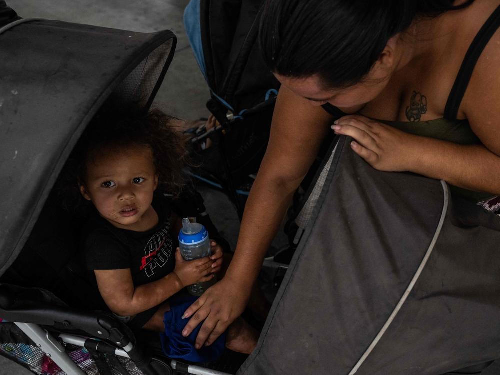 A woman wipes her son with a wet cloth as her family waits at a bus station in Tucson, Ariz. On Wednesday, Tucson set a new record for consecutive days of 100-plus-degree temperatures with 40, dating back to June 16.